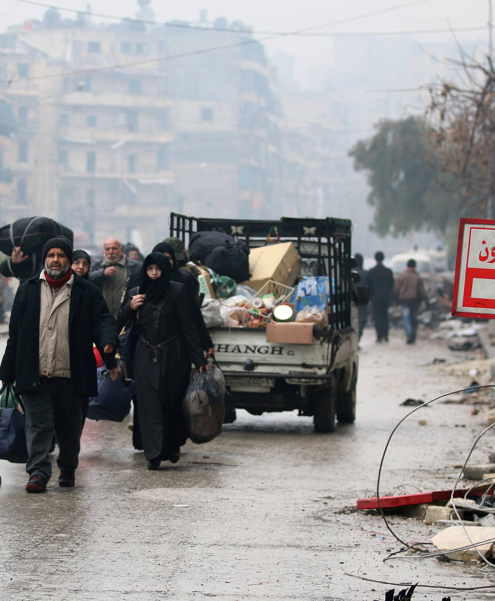 People carry their belongings as they flee deeper into the remaining rebel-held areas of Aleppo