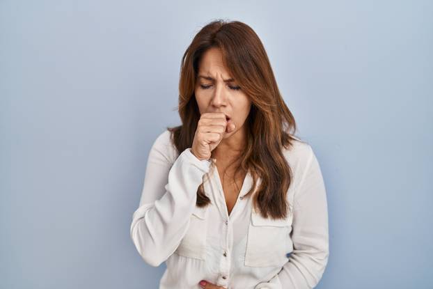 Hispanic woman standing over isolated background feeling unwell and coughing as symptom for cold or bronchitis. health care concept.