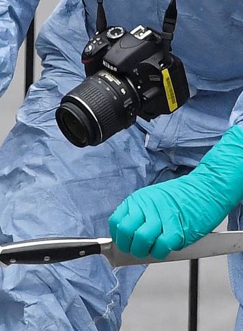A forensic investigator recovers a knife after man was arrested on Whitehall in Westminster, central London
