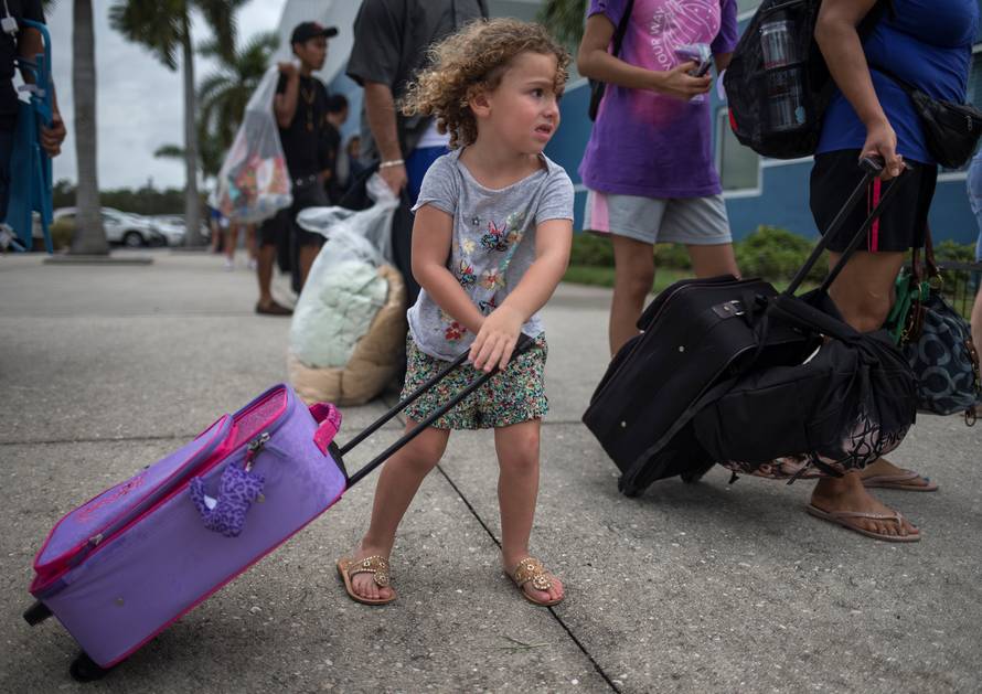A girl carries her belongings into a shelter ahead of the downfall of Hurricane Irma in Estero, Florida