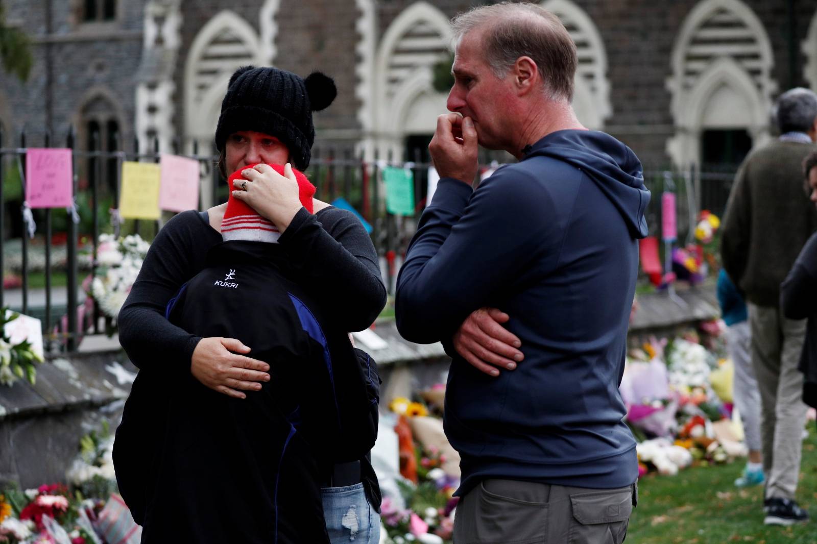 People react at a flower tribute area at Botanical Gardens in Christchurch