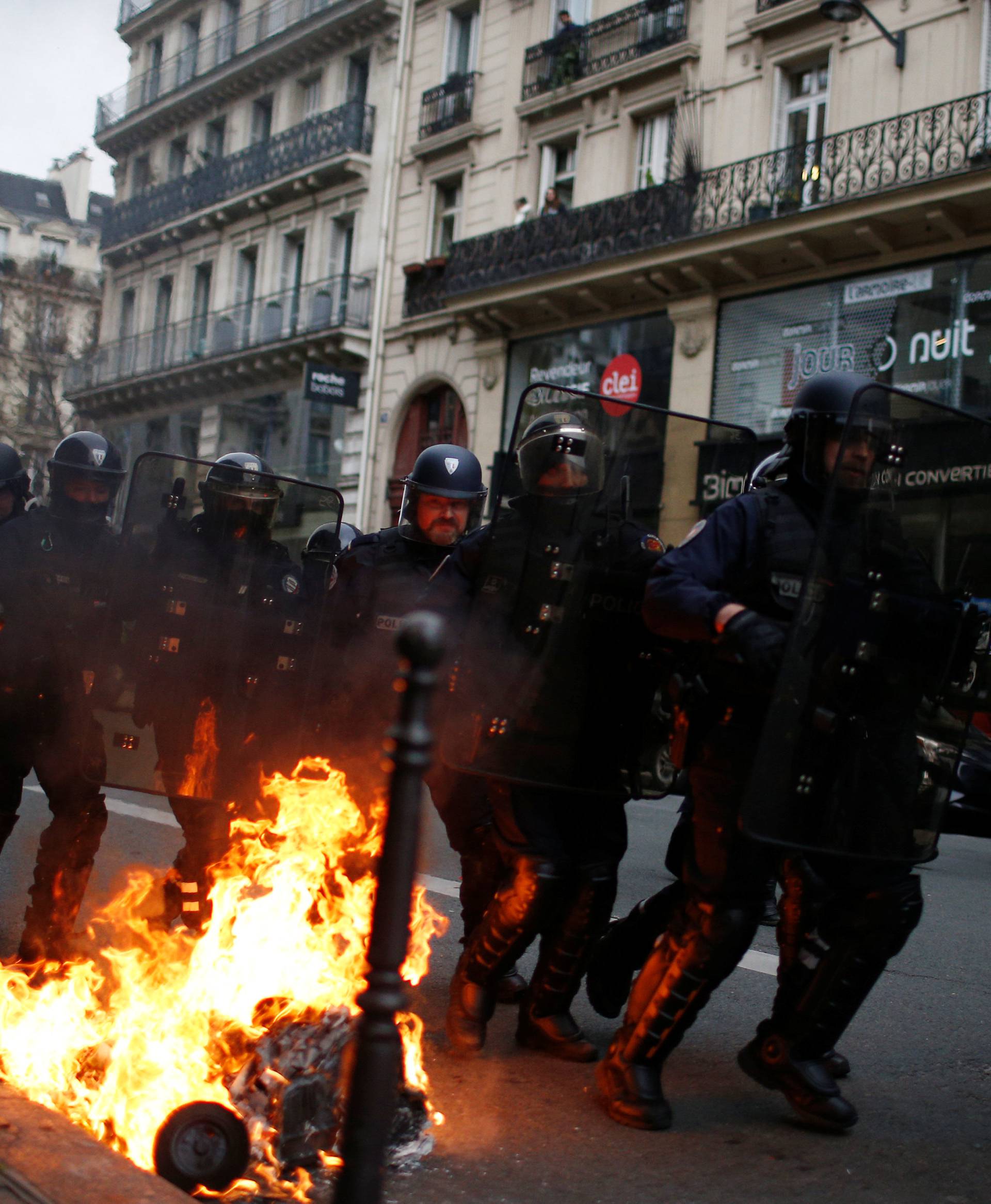 French riot police run in a street during clashes with protesters wearing yellow vests during a national day of protest by the "yellow vests" movement in Paris