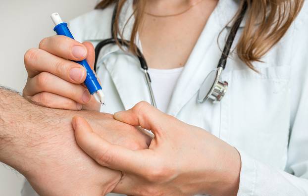 Doctor removing a tick with tweezers from hand of patient