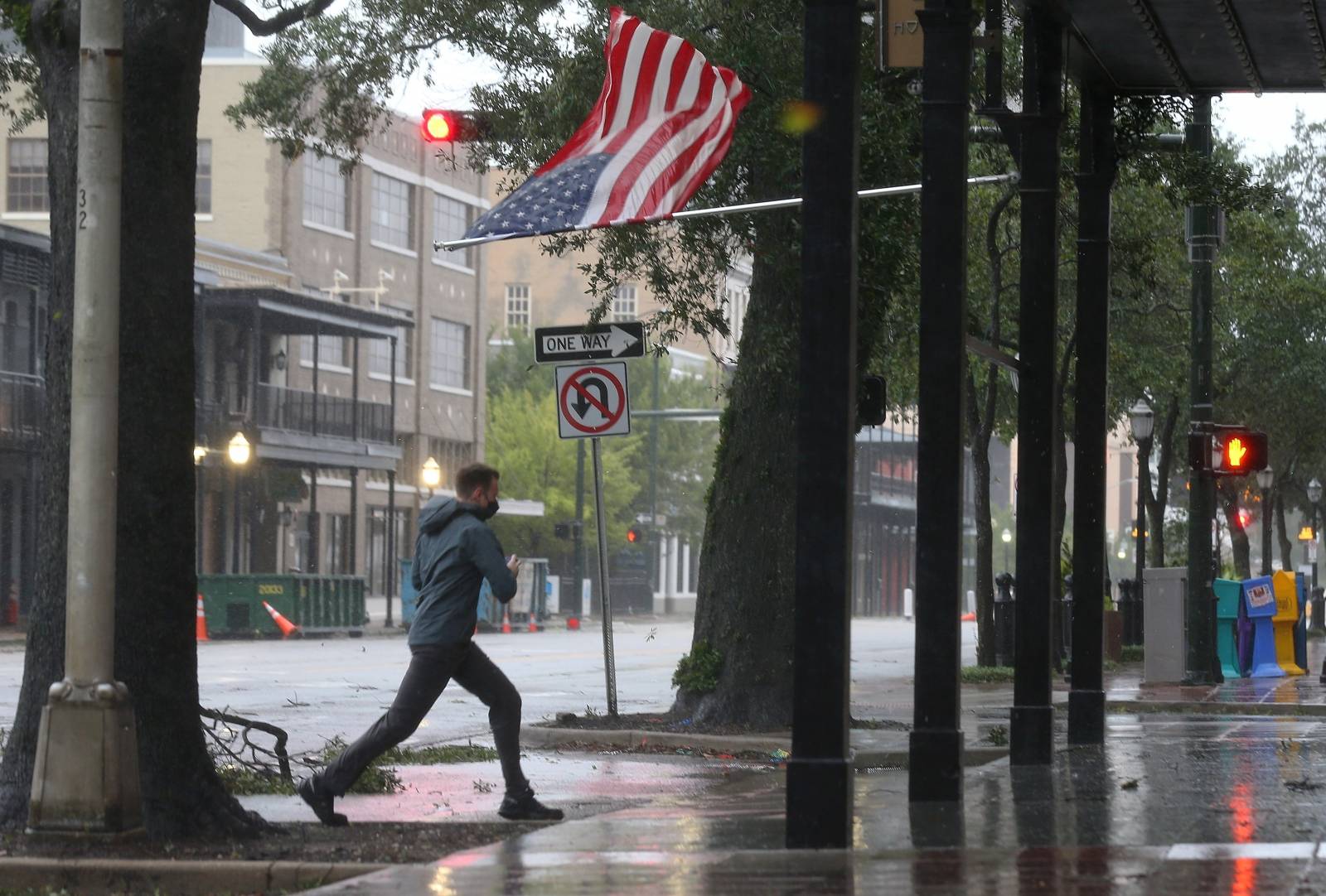 A man walks past an American flag during Hurricane Sally in Mobile