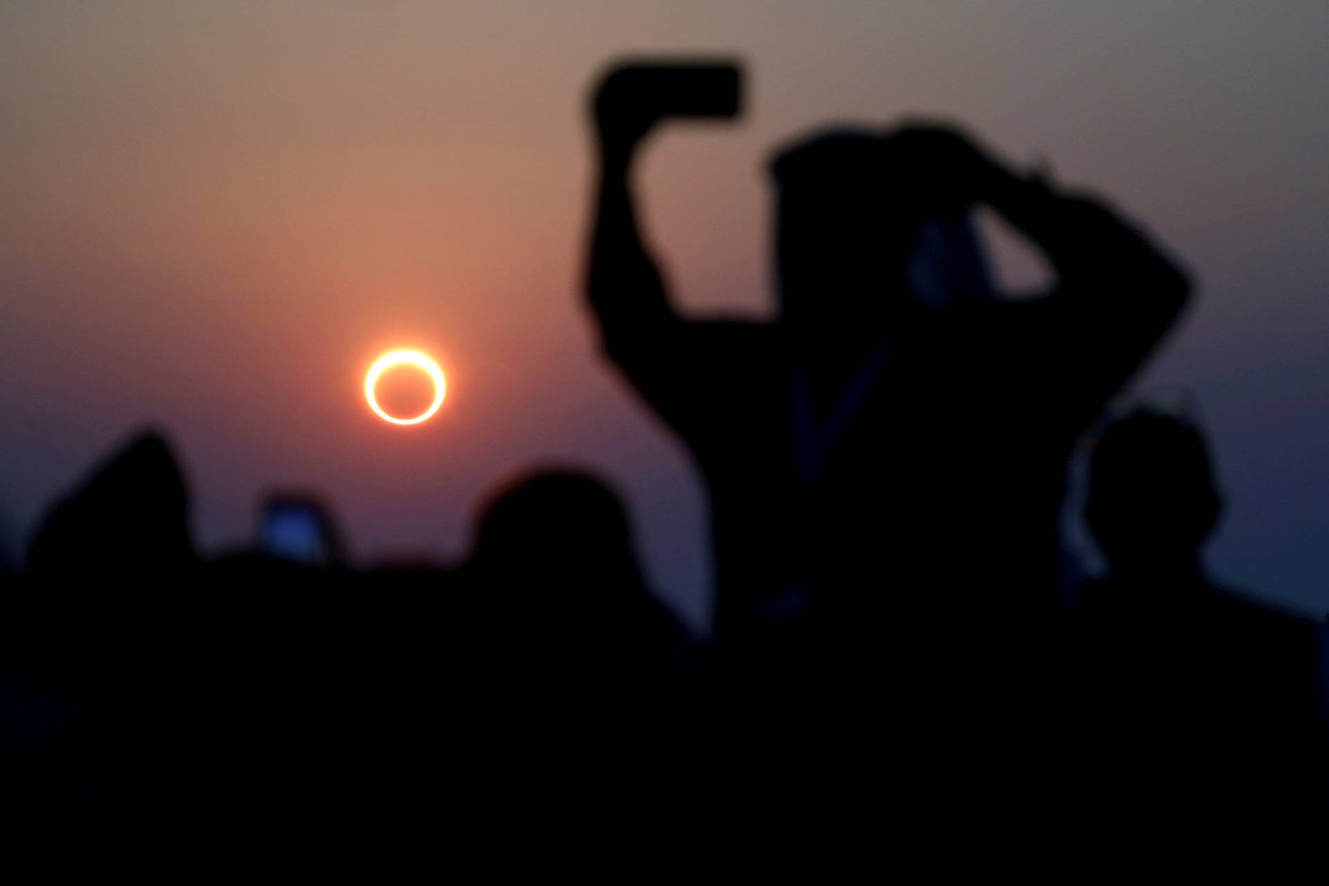 FILE PHOTO: People take photos with their smartphones as they monitor the annular solar eclipse on Jabal Arba (Four Mountains) in Hofuf