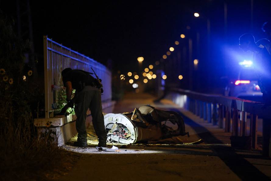 Israeli security and rescue personel work next to a part of a projectile following a Missile attack from Iran towards Israel in northern Israel