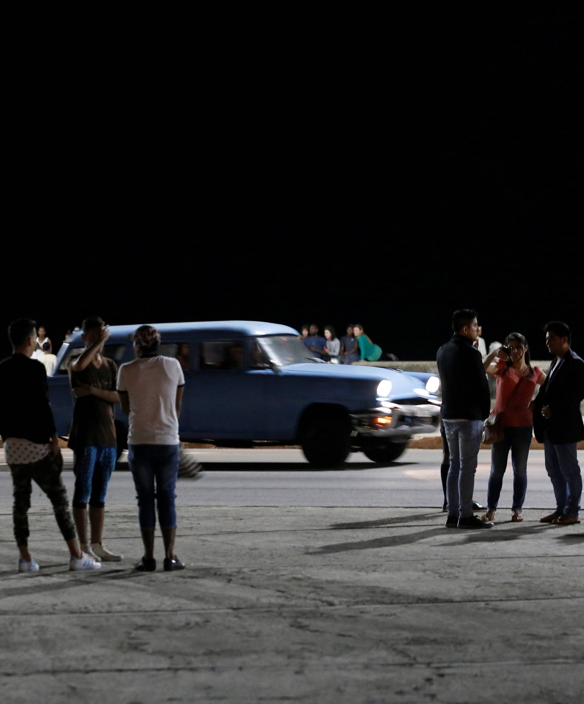 People stand on the seafront boulevard El Malecon in Havana