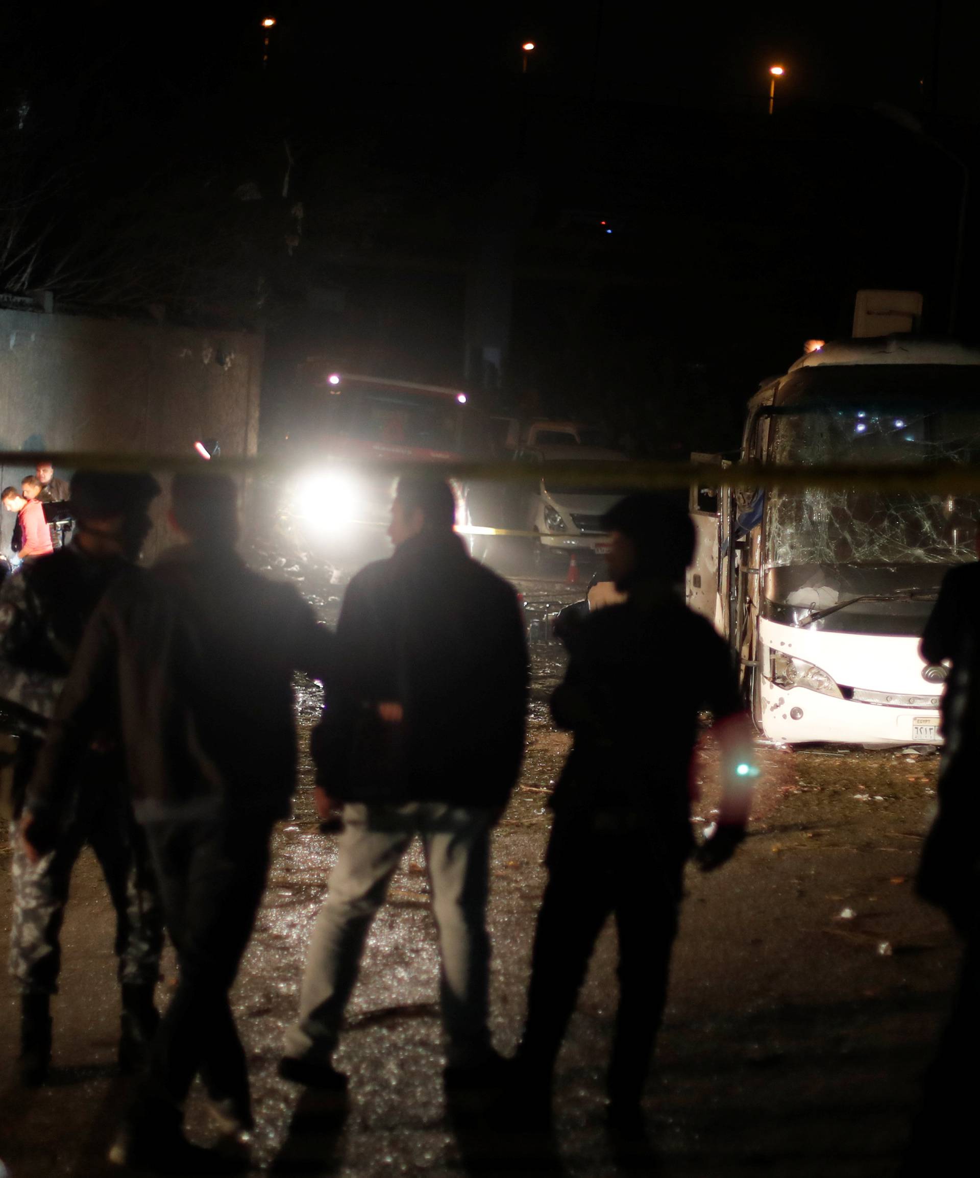 Police officers inspect a scene of a bus blast in Giza