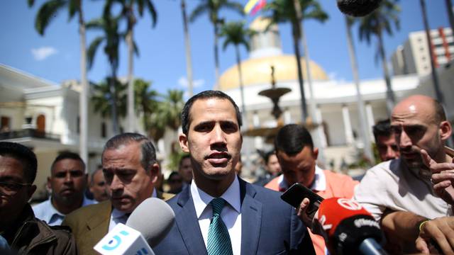 Venezuelan opposition leader Juan Guaido walks as he speaks to journalists before a news conference at the National Assembly in Caracas