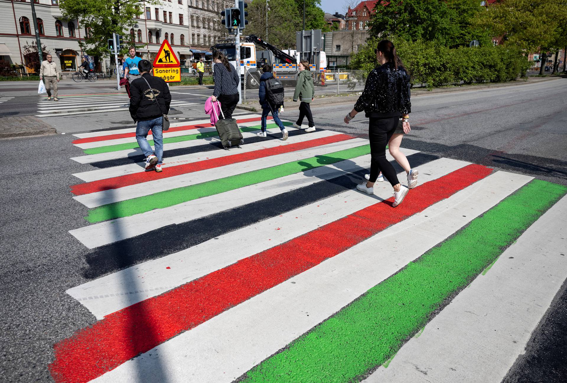 People walk across a zebra crossing painted in the Palestinian colours in Malmo