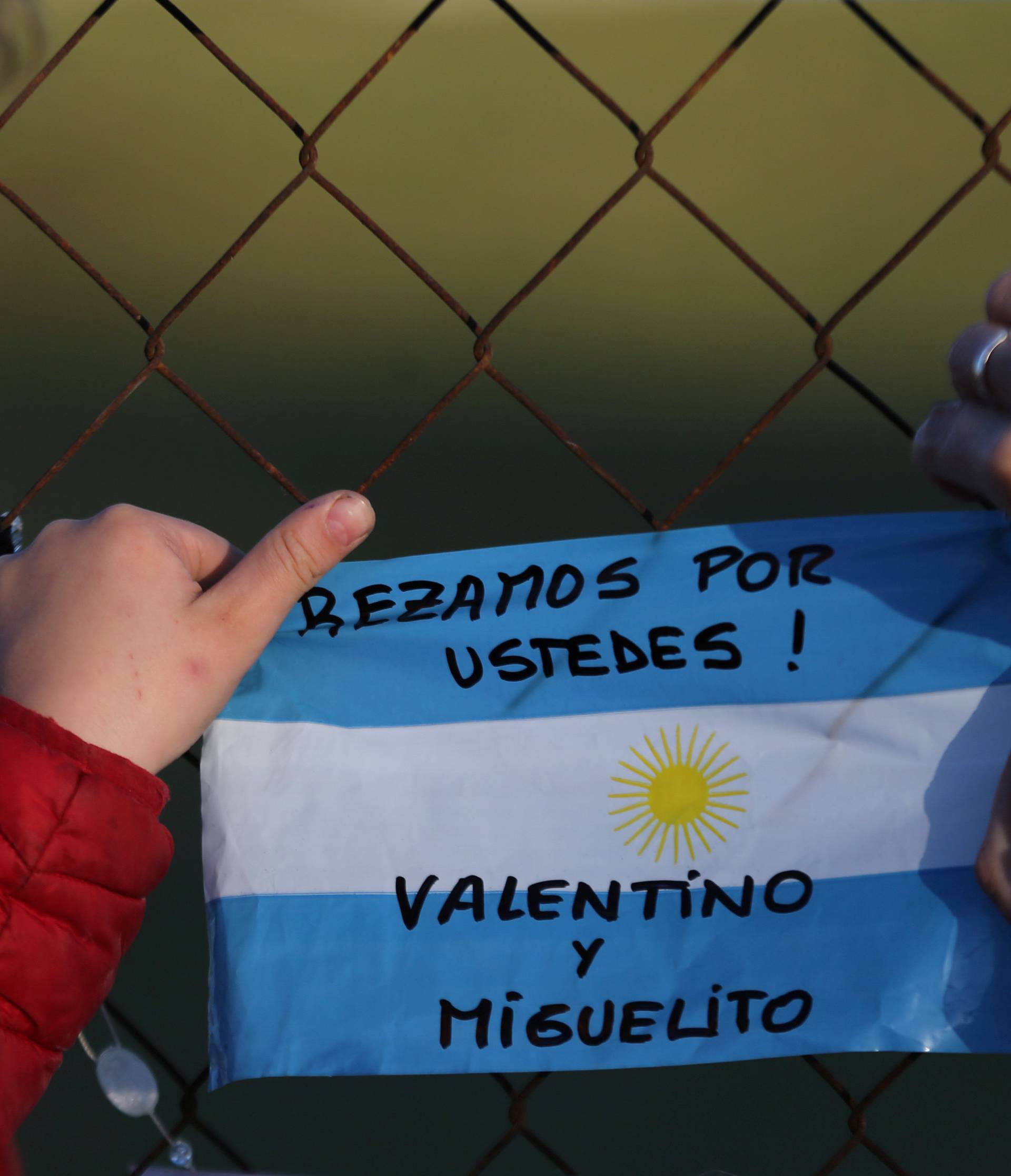 A boy and a woman place an Argentina national flag with a message that reads "We pray for you!" in support of the 44 crew members of the missing at sea ARA San Juan submarine, on a fence at an Argentine naval base in Mar del Plata