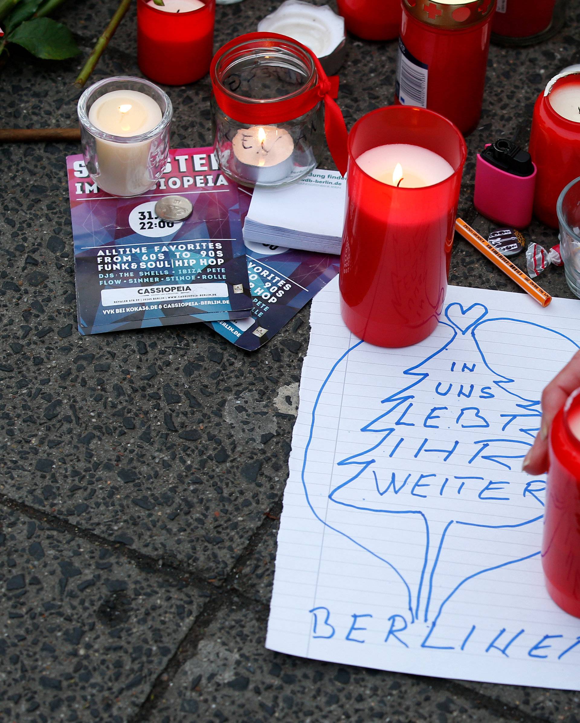 A man lights a candle near the scene where a truck ploughed into a crowded Christmas market in the German capital last night in Berlin