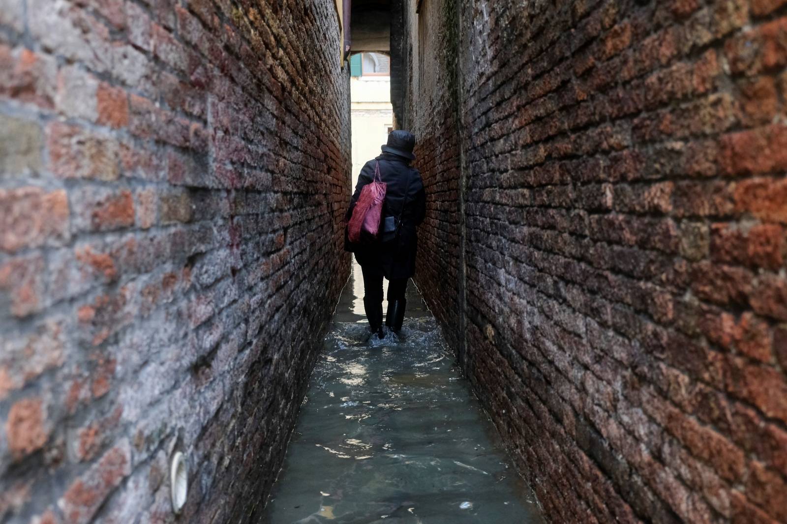 A woman walks in the flooded street during a period of seasonal high water in Venice