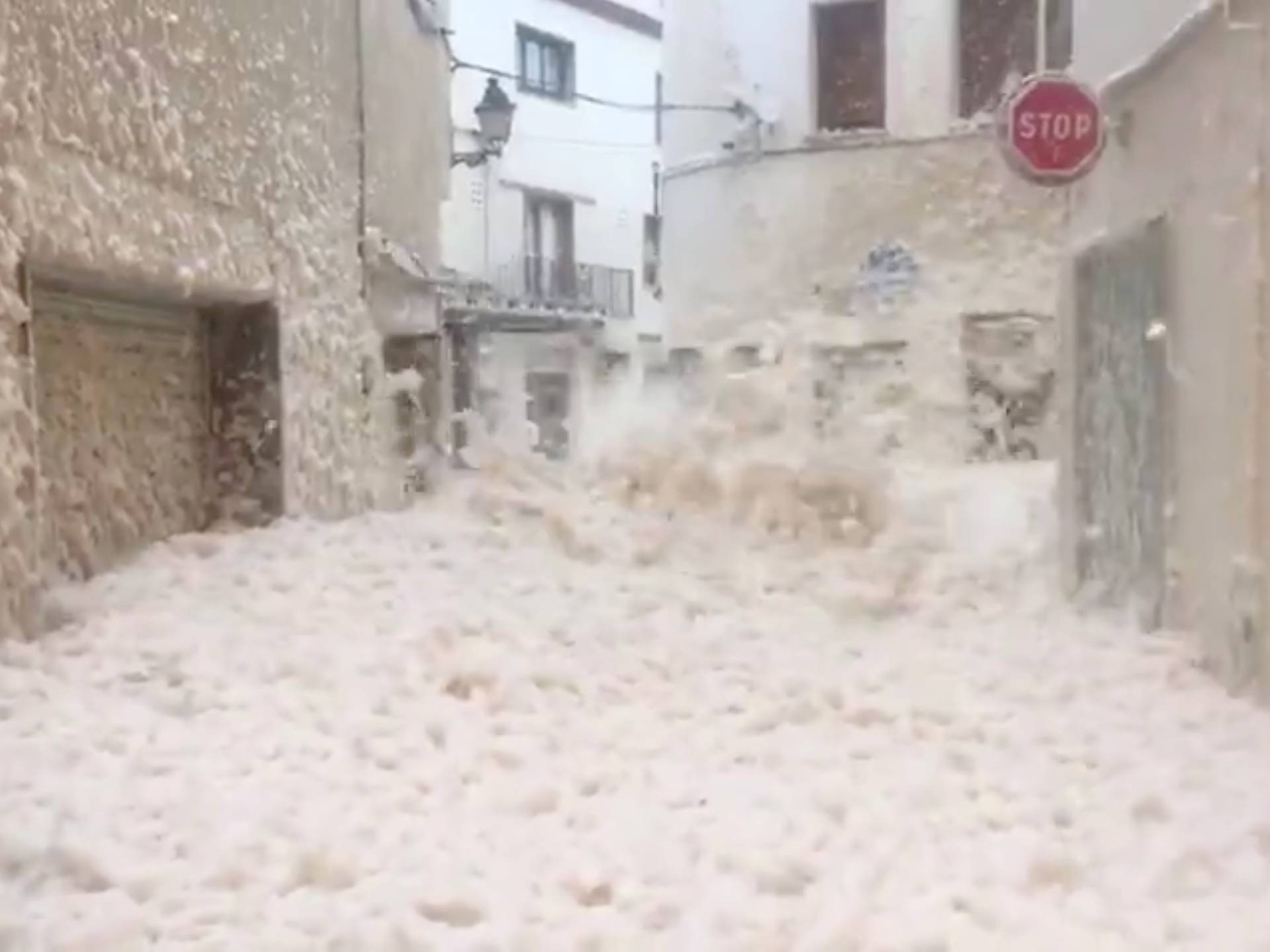 Strong winds blow thick sea foam through the streets of Tossa De Mar