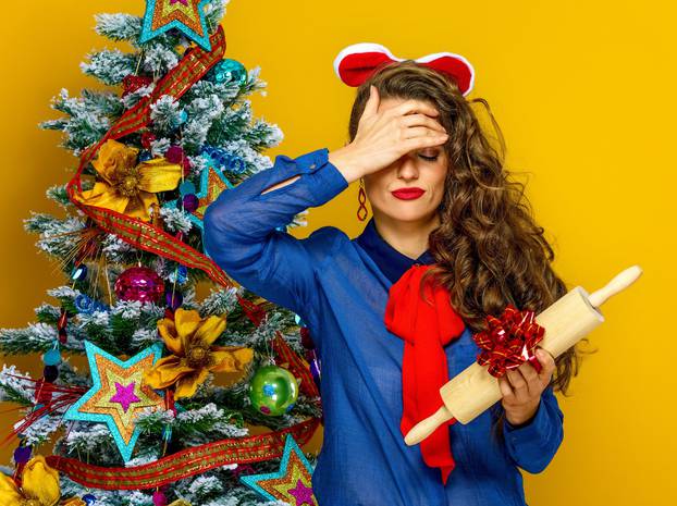 woman near Christmas tree holding unwanted present