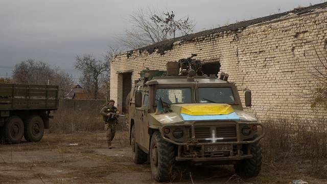 Ukrainian service member stands next to a previously captured Russian armoured personnel carrier in the village of Blahodatne in Kherson region