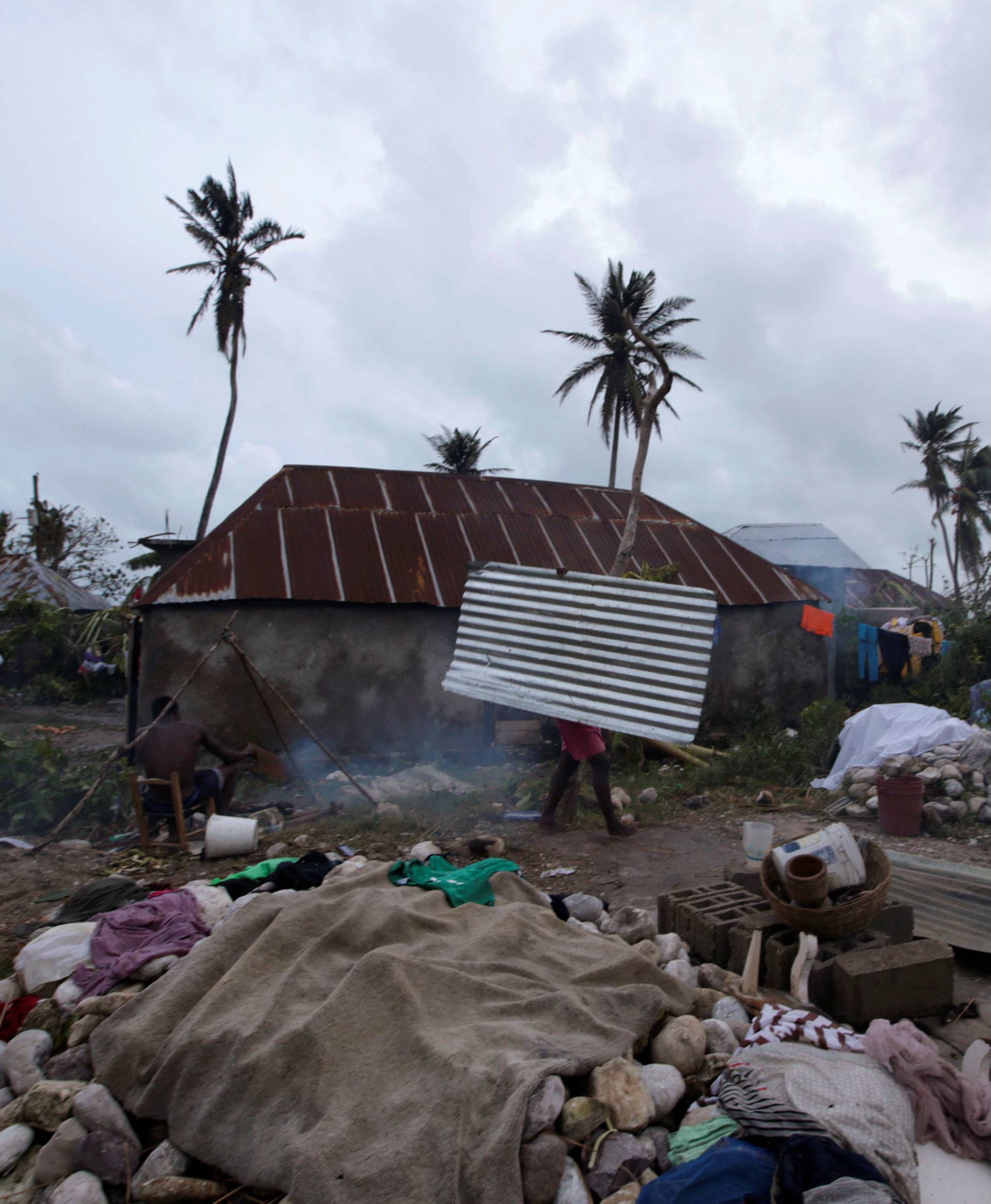 A woman carries a tin sheet after Hurricane Matthew in Les Cayes, Haiti