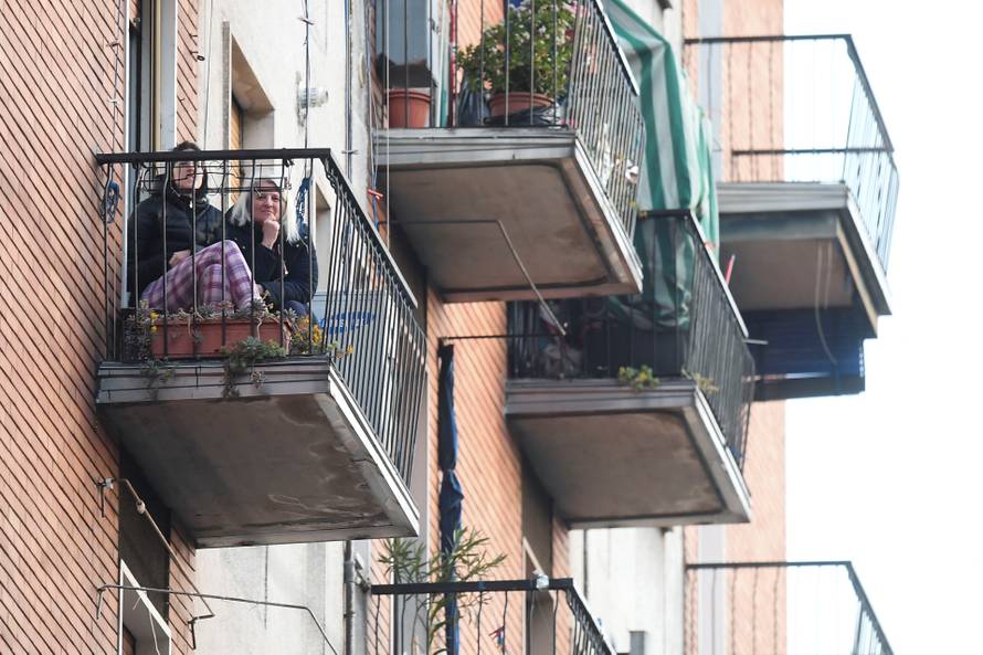 Woman listen to music as a neighbor plays the guitar from a balcony to raise morale on the sixth day of an unprecedented lockdown across of all Italy imposed to slow the outbreak of coronavirus in Milan