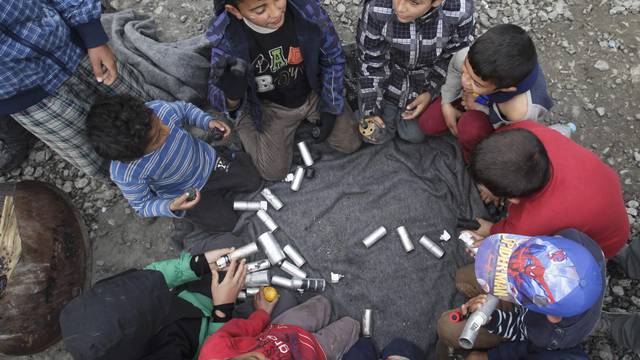 Migrant children play with rubber bullets and empty cases at a makeshift camp for refugees and migrants at the Greek-Macedonian border near the village of Idomeni