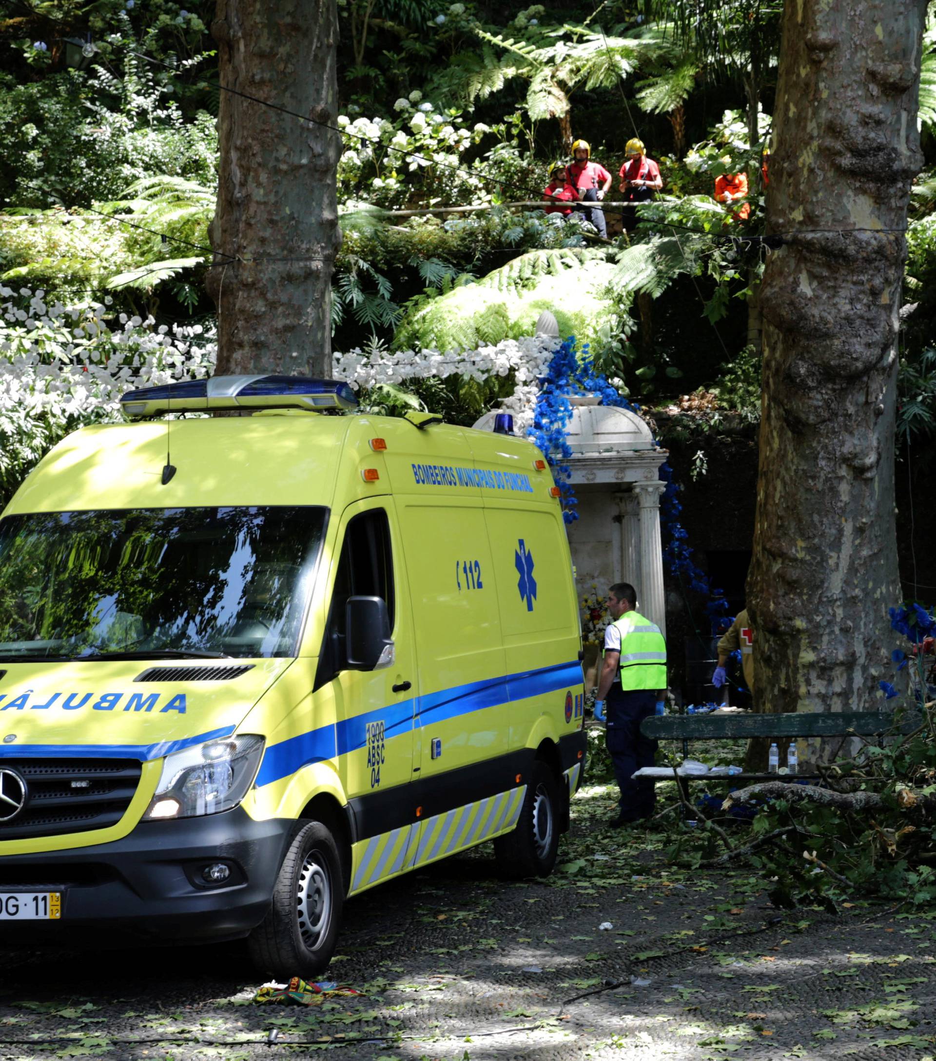 Firefighters cover victims of a tree that toppled into worshipping crowds during a religious festival in Funchal