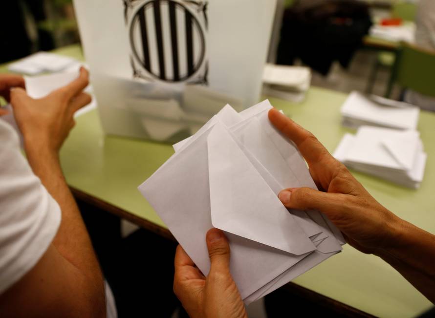 Poll workers count ballots after polls closed at a polling station for the banned independence referendum in Barcelona