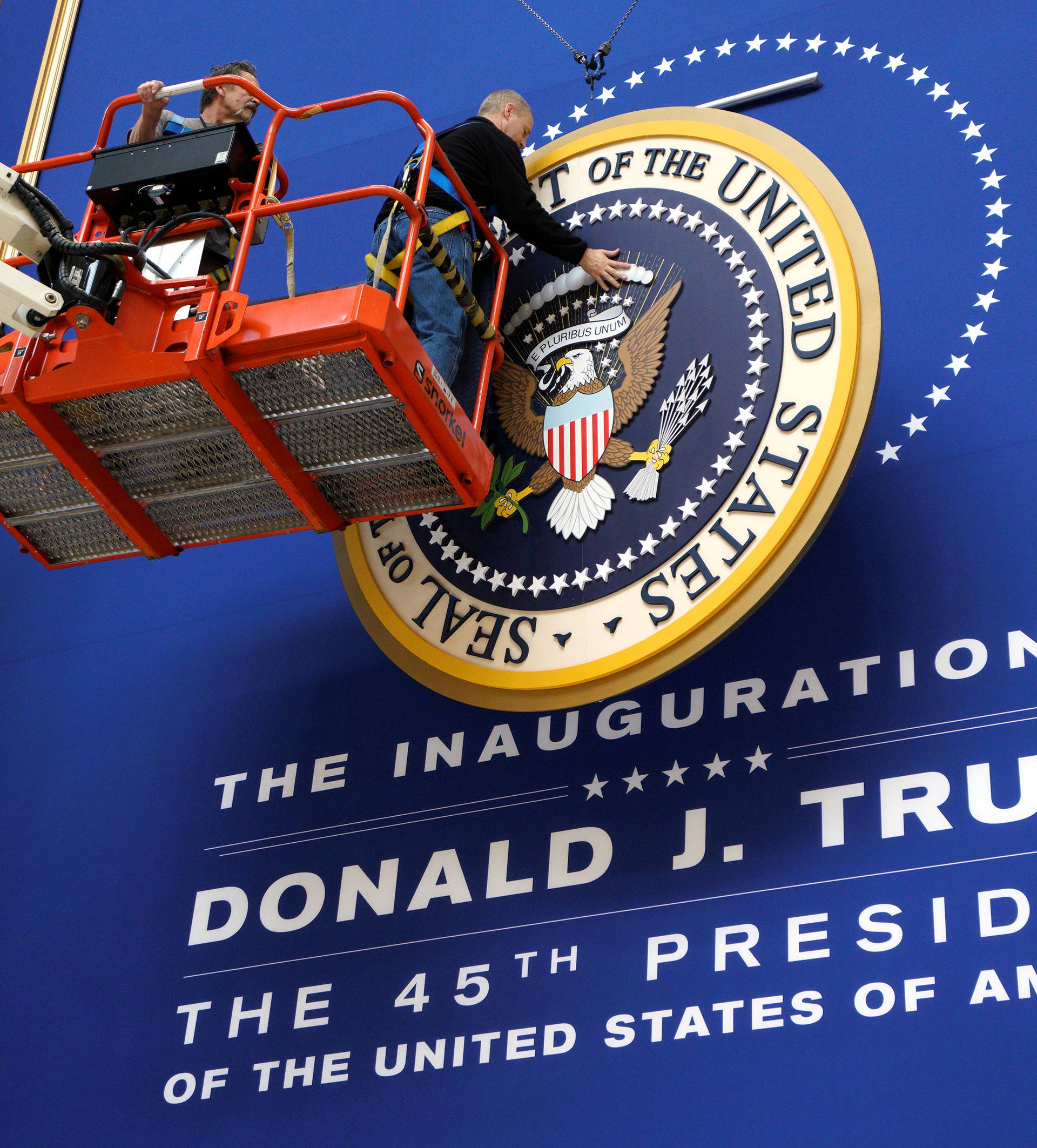 Workers install the presidential seal at the site of the Commander in Chief inaugural ball for President-elect Donald Trump in Washington, DC