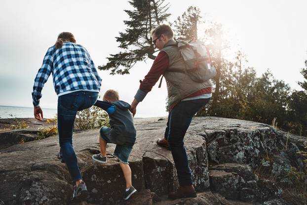 Careful now. Rearview shot of a cheerful young family holding hands and walking together up a hill outside during the day.