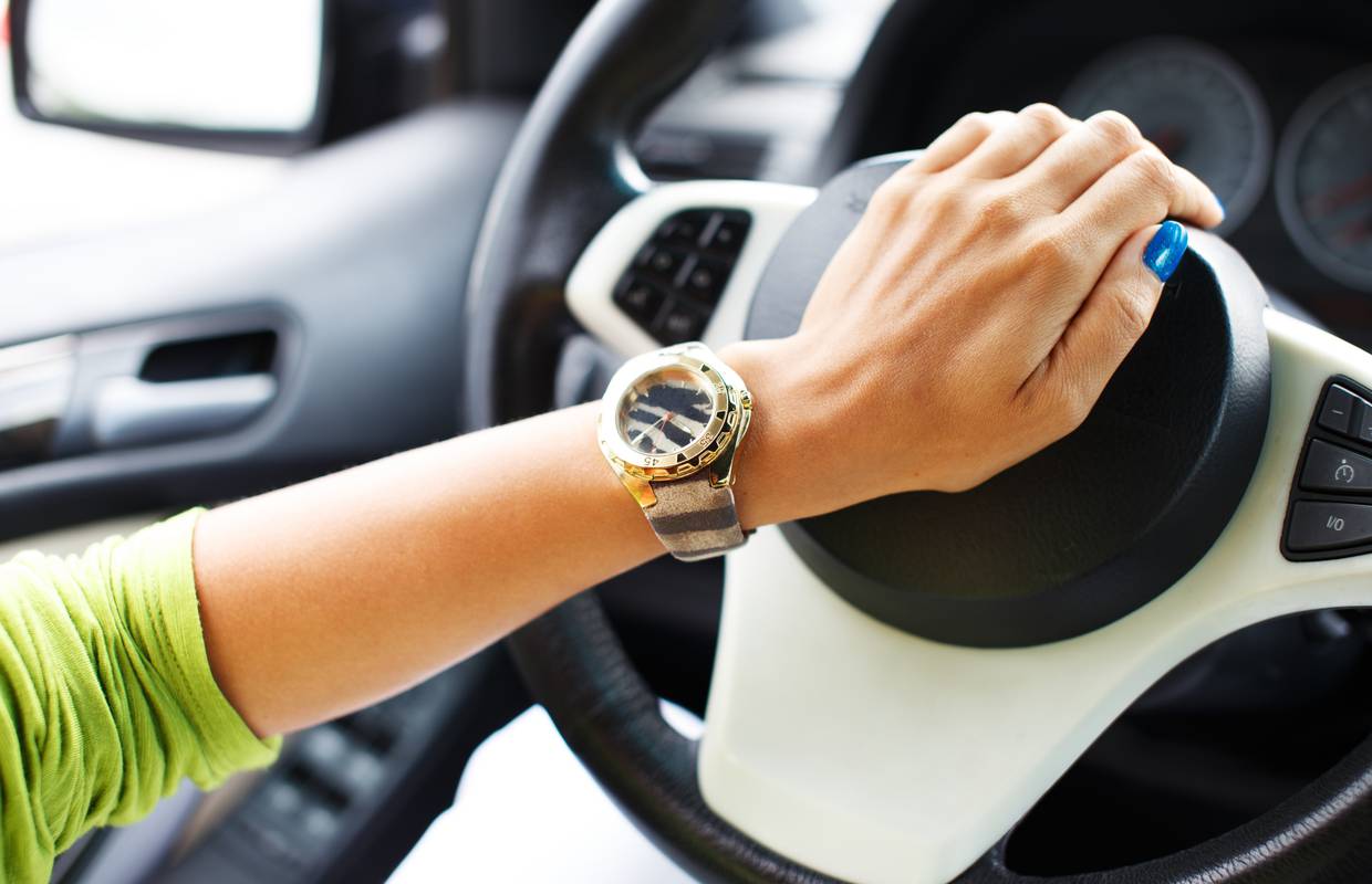 Женская рука с часами на руле