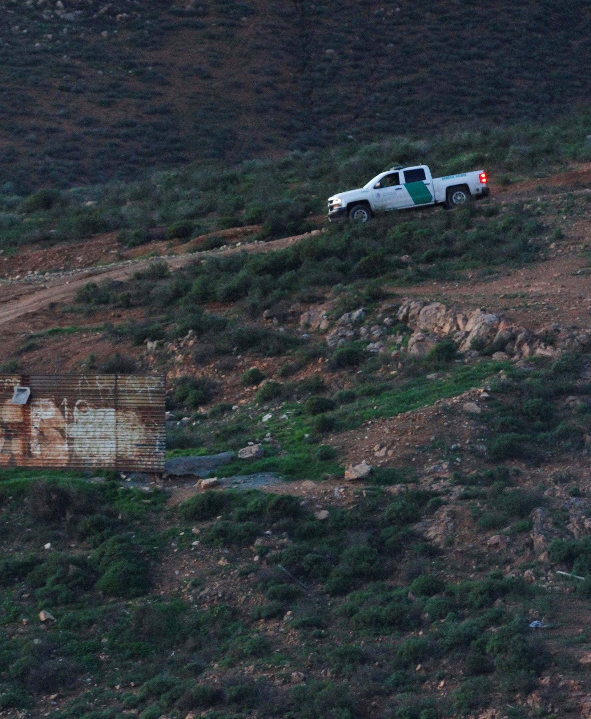 A U.S. police patrol vehicle is seen behind a section of the wall separating Mexico and the United States, in Tijuana