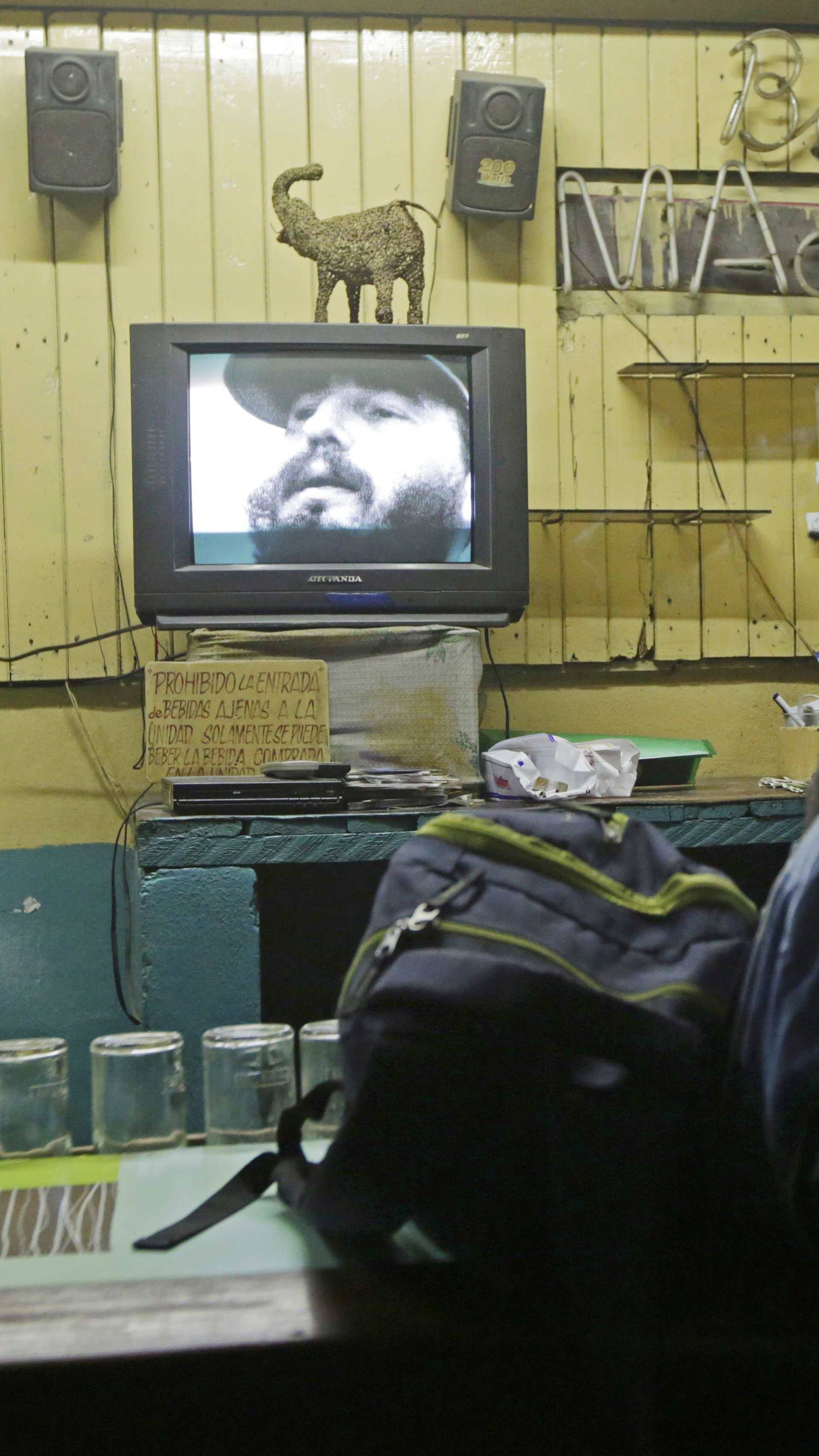 A man watches a television broadcast with the image of Cuba's former President Fidel Castro in Havana