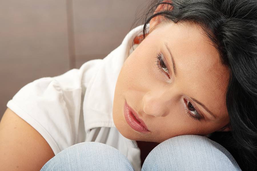 A worried and afraid young woman sitting on the flor.