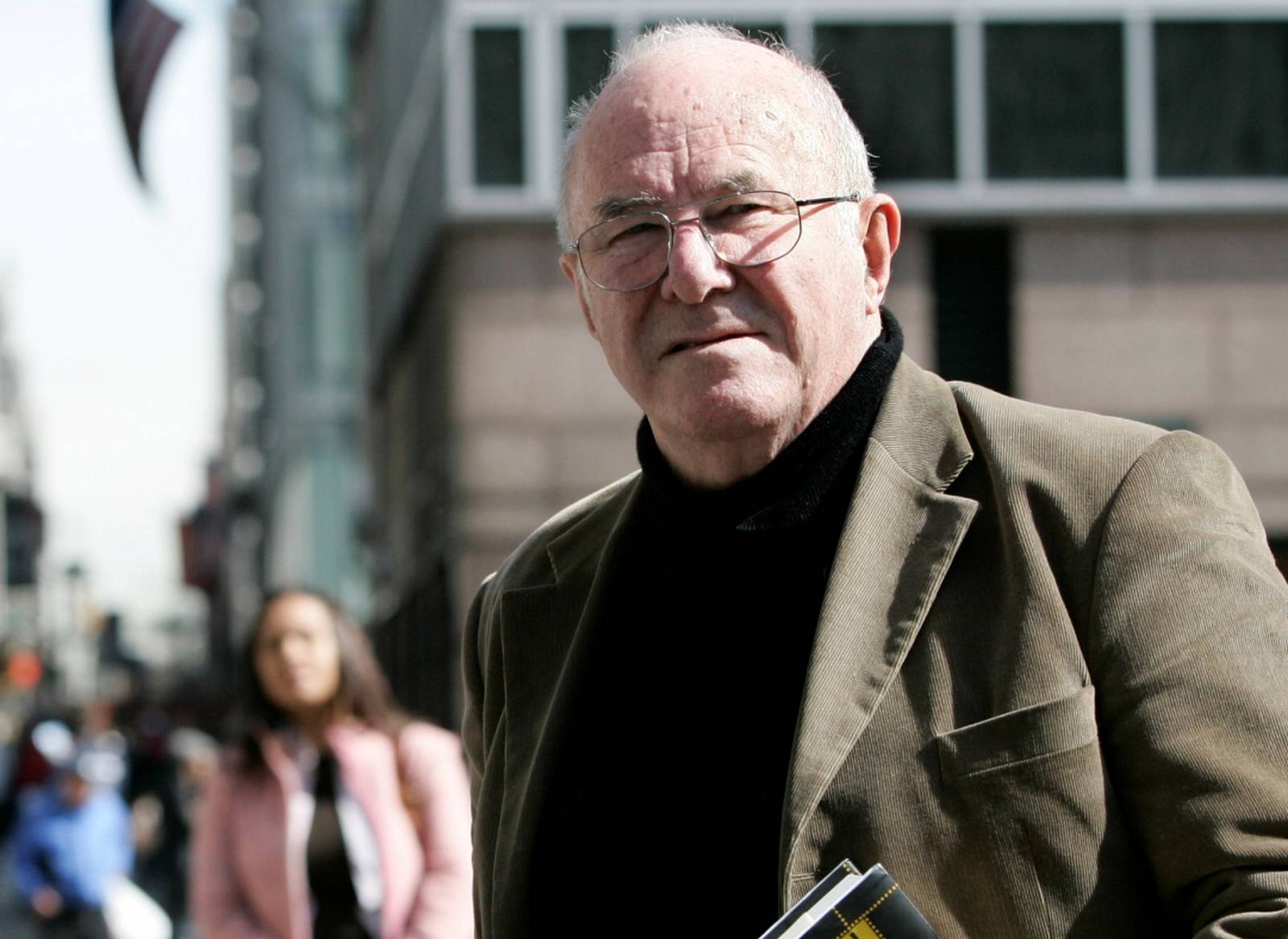 FILE PHOTO: Author Clive James poses with copy of his latest book "Cultural Amnesia" in New York