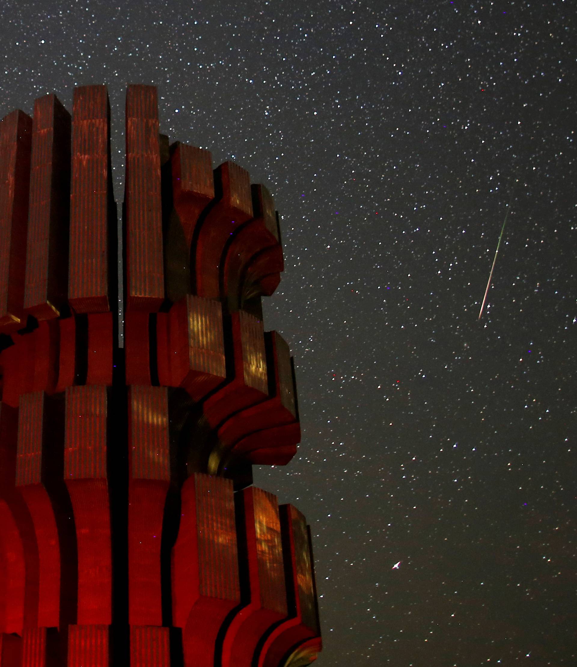 Meteor streaks across skies near the Monument to the Revolution in Prijedor