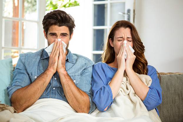 Young couple blowing their nose in tissue