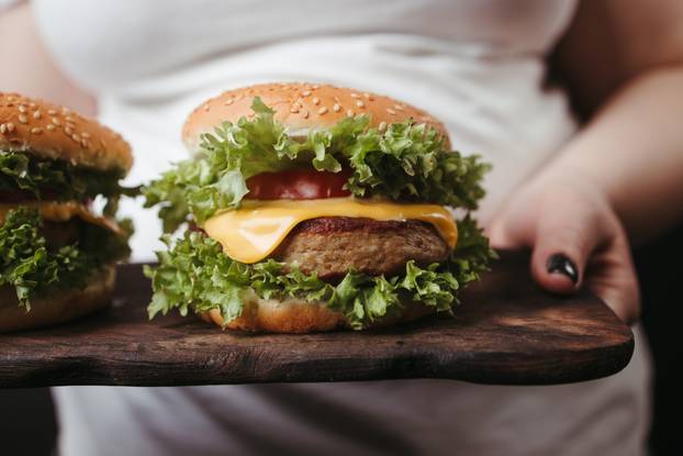 Obese woman with two tasty fattening hamburgers