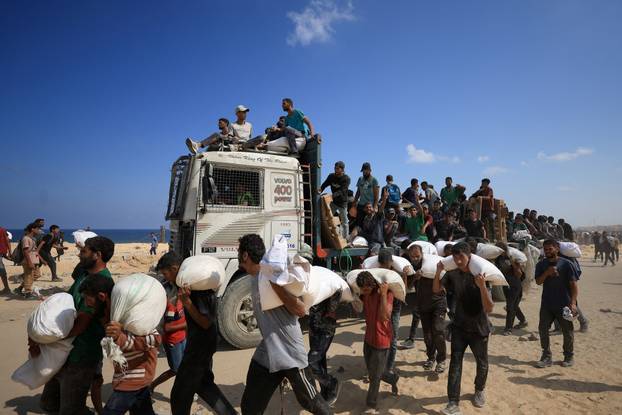 Palestinians gather to receive aid supplies amid a hunger crisis, in Beit Lahia