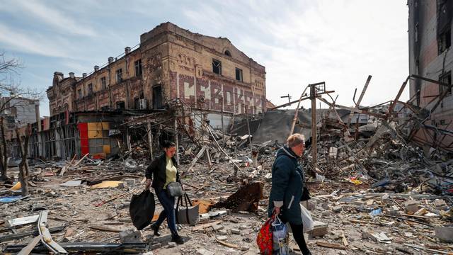 FILE PHOTO: Residents carry their belongings near buildings destroyed in the course of the Ukraine-Russia conflict, in Mariupol