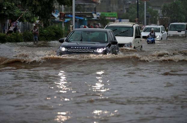 Vehicles move through a water-logged road after heavy rains in Ahmedabad