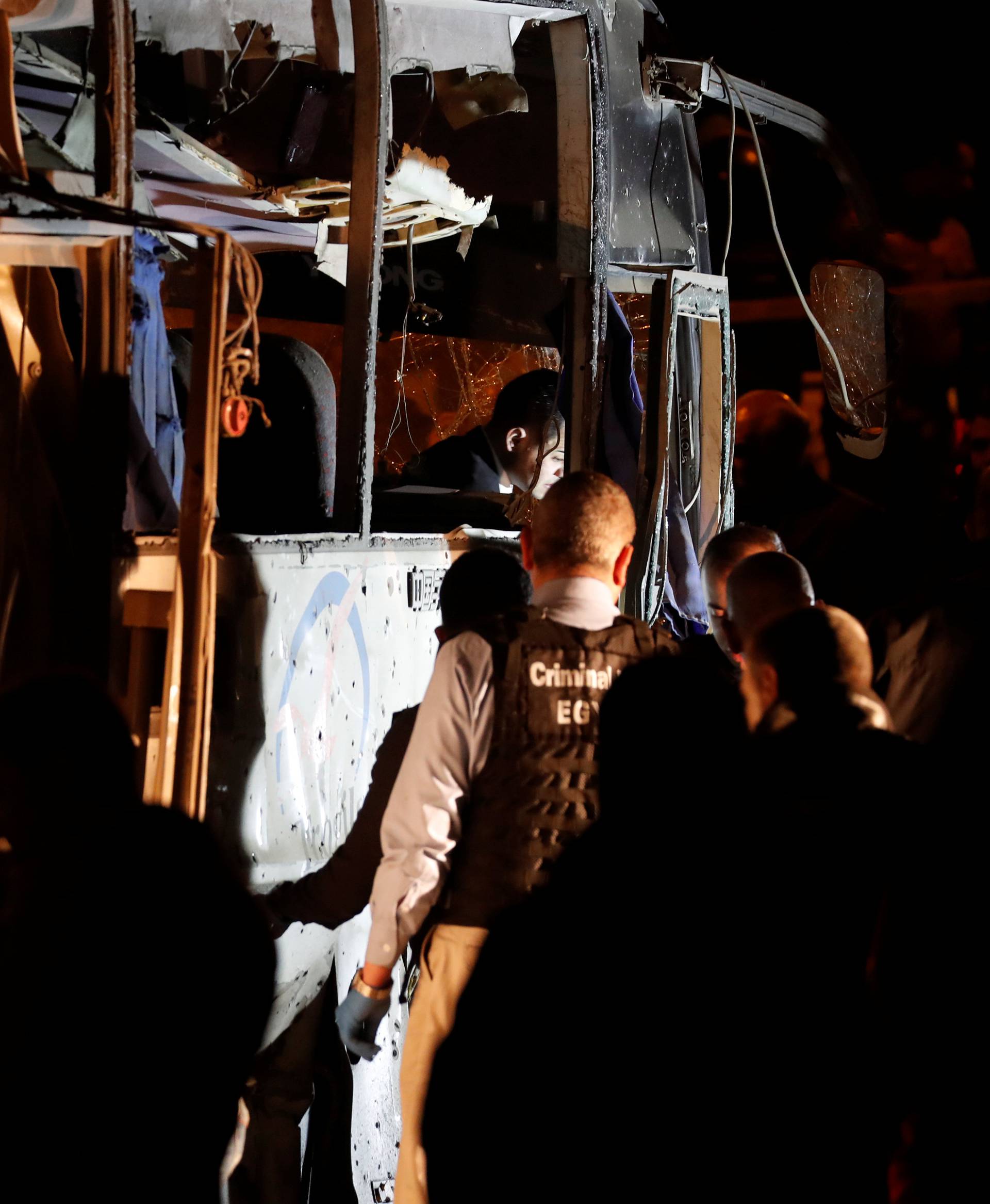 Police officers and officials inspect a scene of a bus blast in Giza