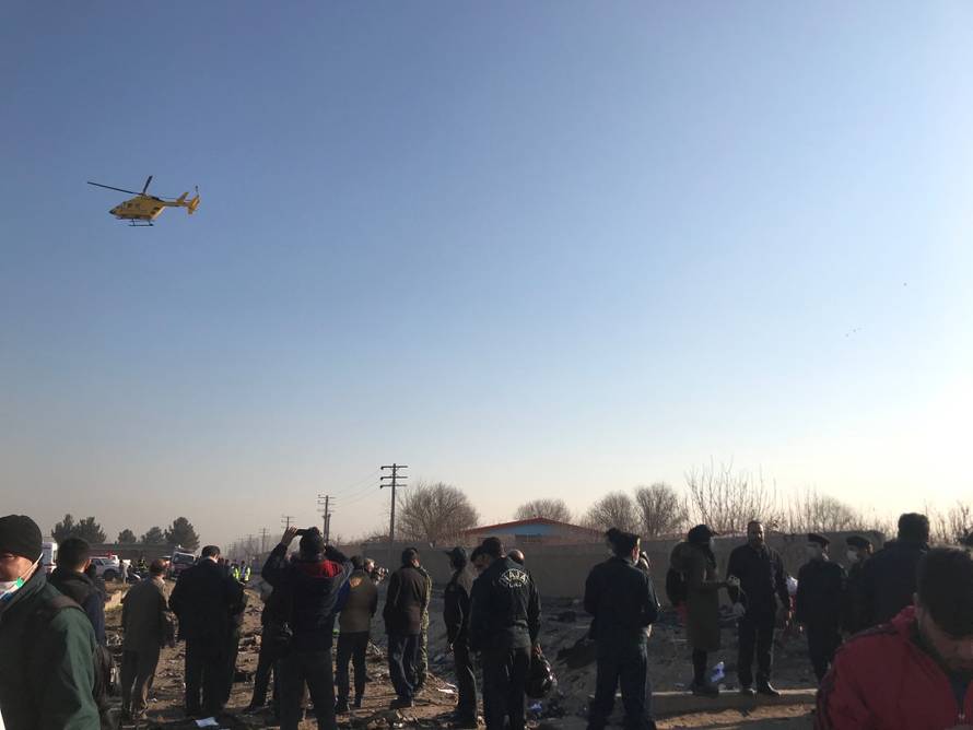 Rescue team members with people check the debris from a plane crash belonging to Ukraine International Airlines after take-off from Iran's Imam Khomeini airport, on the outskirts of Tehran
