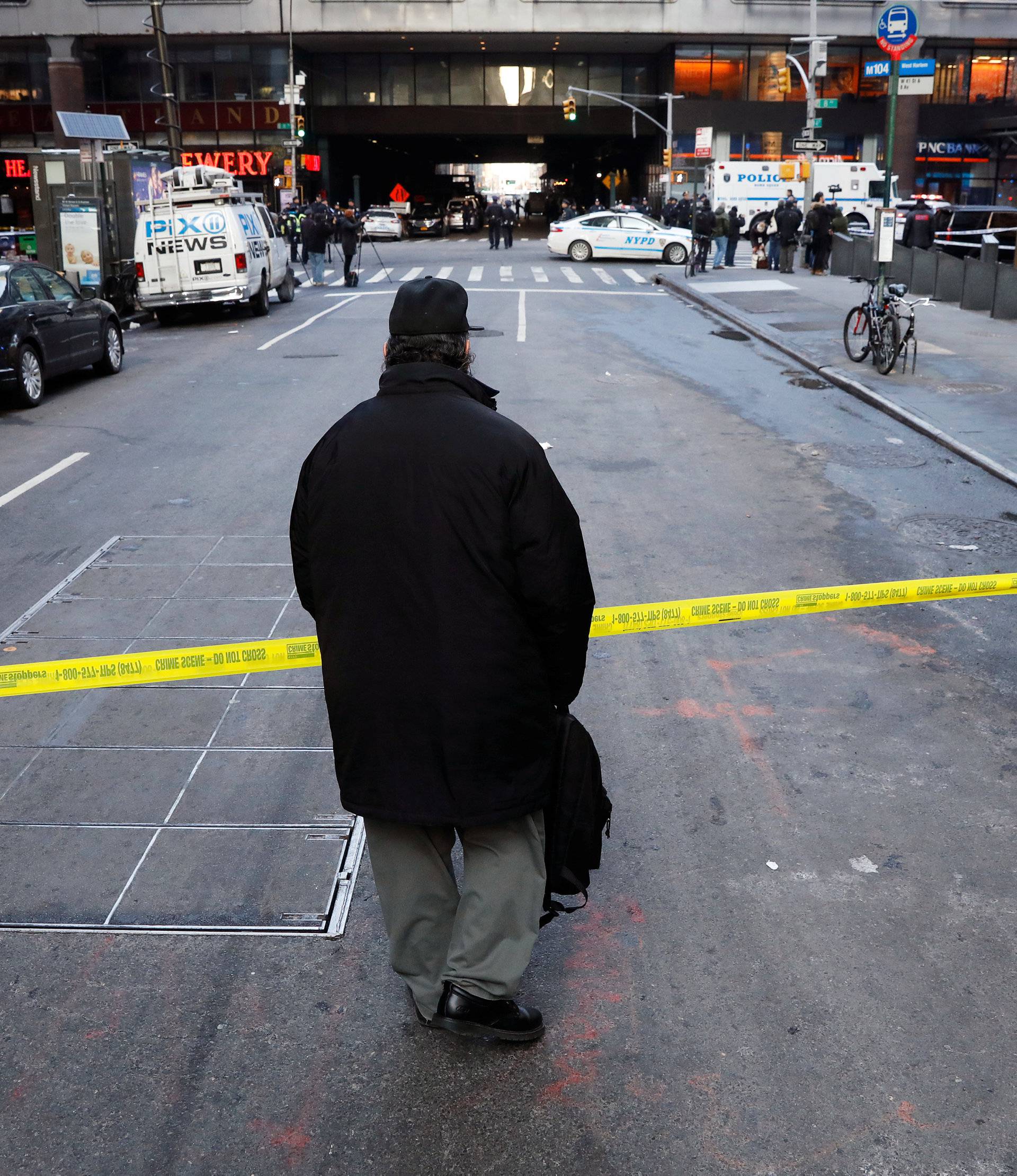 A passer-by looks over the police tape outside the New York Port Authority Bus Terminal in New York City after reports of an explosion