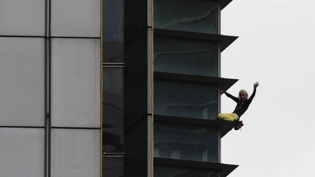 French climber Robert waves as he climbs down the 47-storey GT International Tower in Makati City