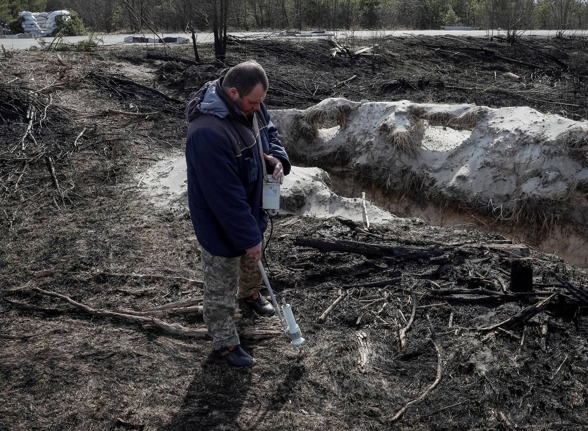 A dosimetrist measures the level of radiation around trenches dug by the Russian military in an area with high levels of radiation called the Red Forest near the Chernobyl Nuclear Power Plant, in Chernobyl