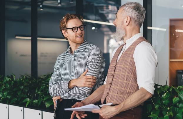 Two,Caucasian,Male,Colleagues,Smiling,And,Chatting,In,Modern,Office