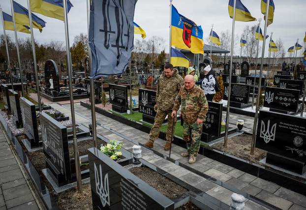 People visit graves of killed Ukrainian defenders, on the day of the second anniversary of Russia's attack on Ukraine, in the town of Bucha