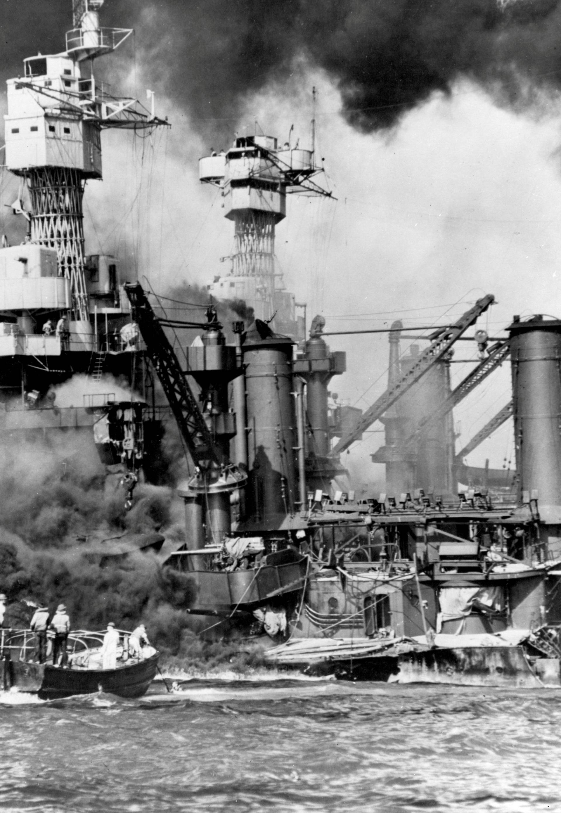 Archive photo of sailors in a motor launch rescuing a survivor from the water alongside the sunken USS West Virginia in Pearl Harbor