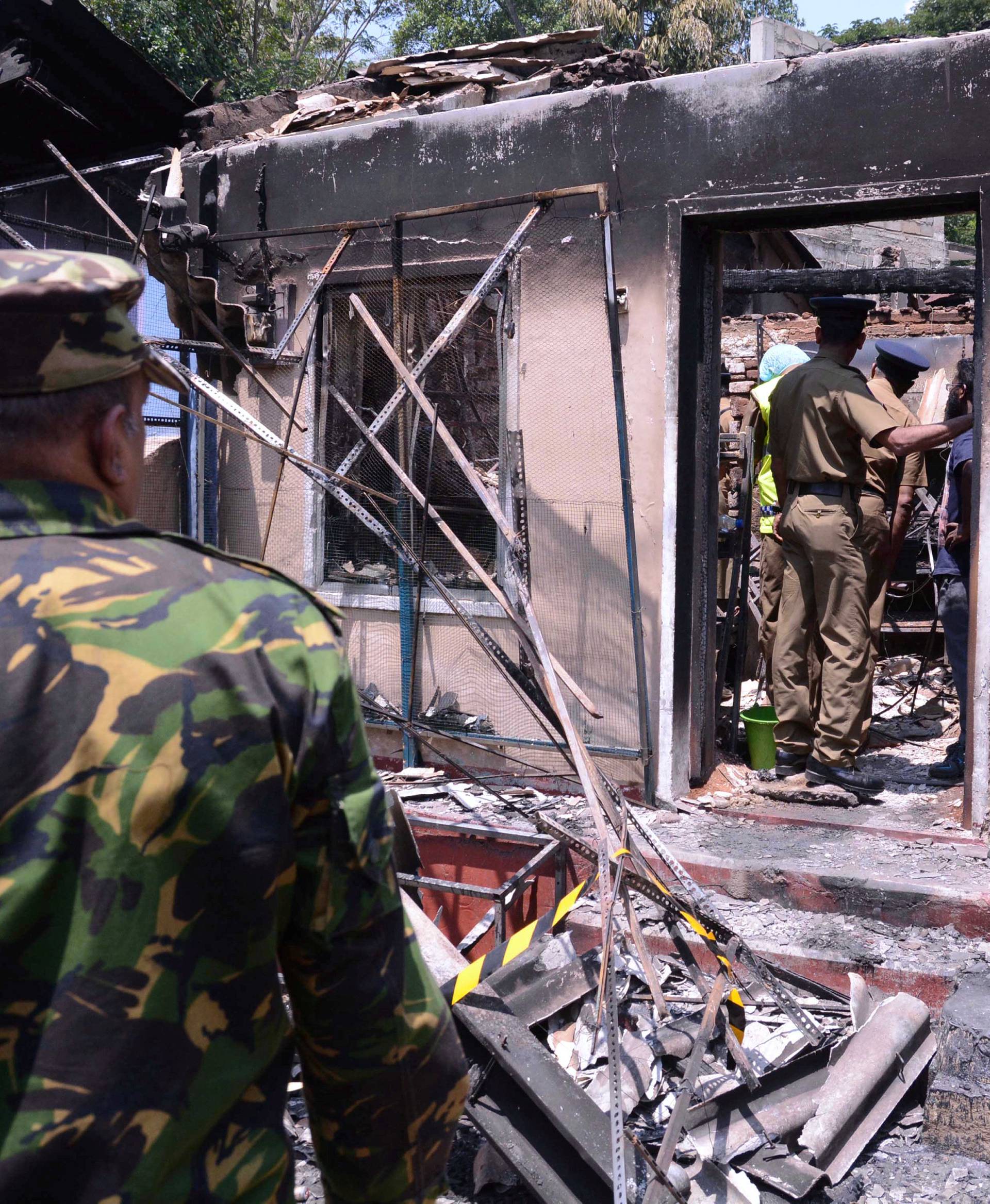 Sri Lanka's Special Task Force and Police officers stand guard near a burnt house after a clash between  two communities in Digana, central district of Kandy