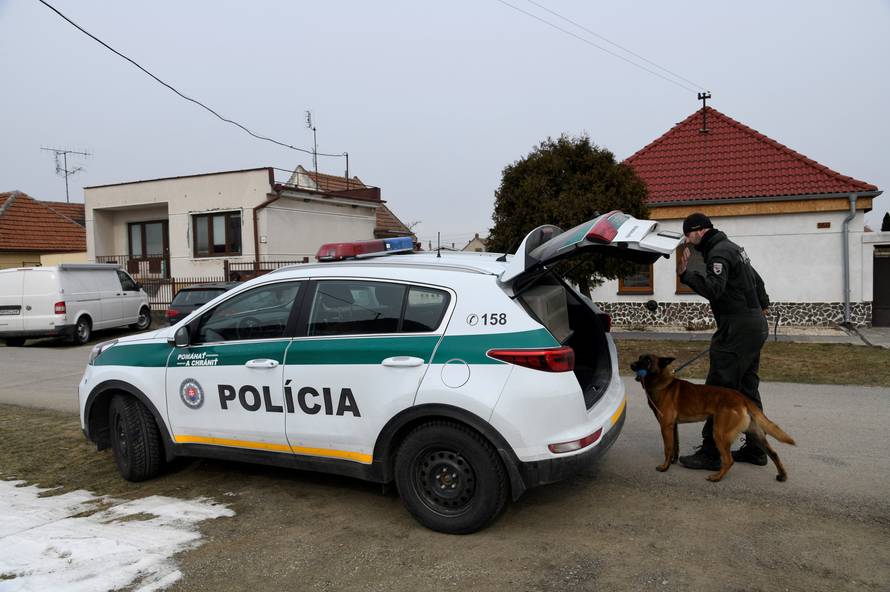 A police officer with a dog is seen near a house where Slovak investigative journalist Jan Kuciak and his girlfriend Martina Kusnirova lived and were murdered in the village of Velka Maca