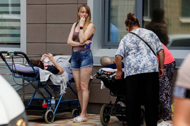 A woman stands next to patients near Ohmatdyt Children's Hospital that was damaged during Russian missile strikes, in Kyiv