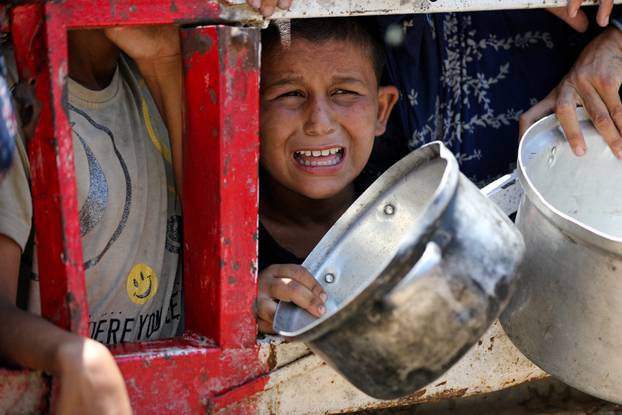 Palestinians gather to receive food from charity kitchen, in Gaza City